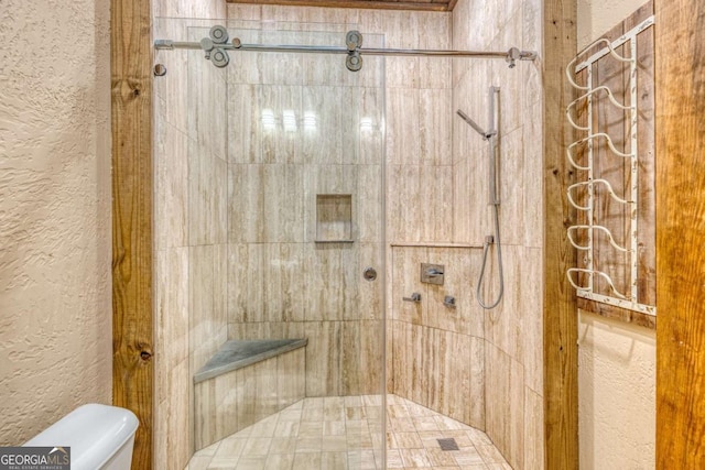 bathroom with toilet and a tile shower