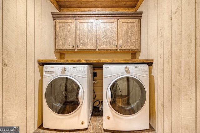 laundry room featuring cabinets, wooden walls, and independent washer and dryer