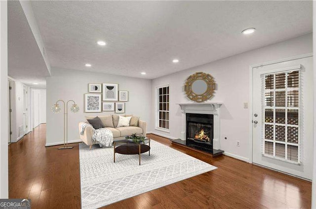 living room featuring a fireplace, dark wood-type flooring, and a textured ceiling