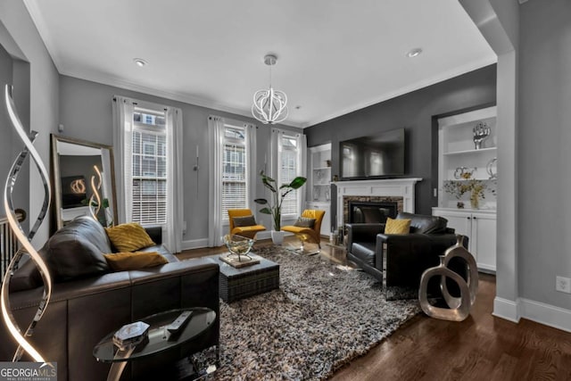 living room with an inviting chandelier, ornamental molding, dark wood-type flooring, and built in features