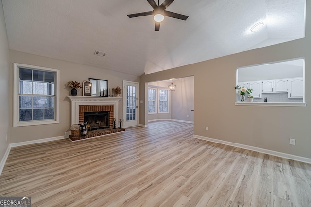 unfurnished living room featuring lofted ceiling, a fireplace, light hardwood / wood-style floors, and ceiling fan