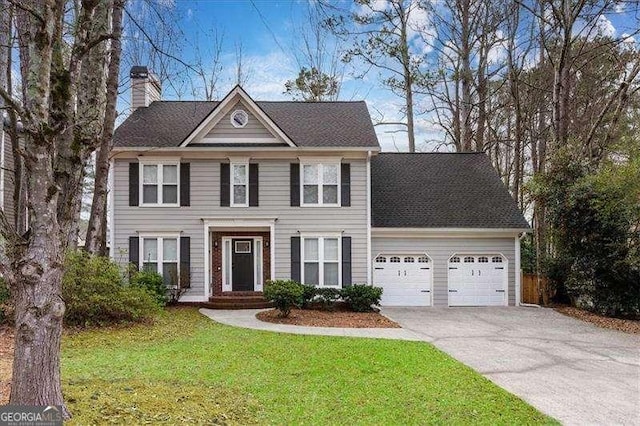 colonial inspired home featuring a garage and a front lawn