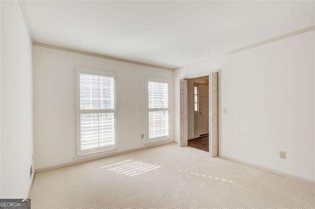 empty room featuring light carpet and crown molding