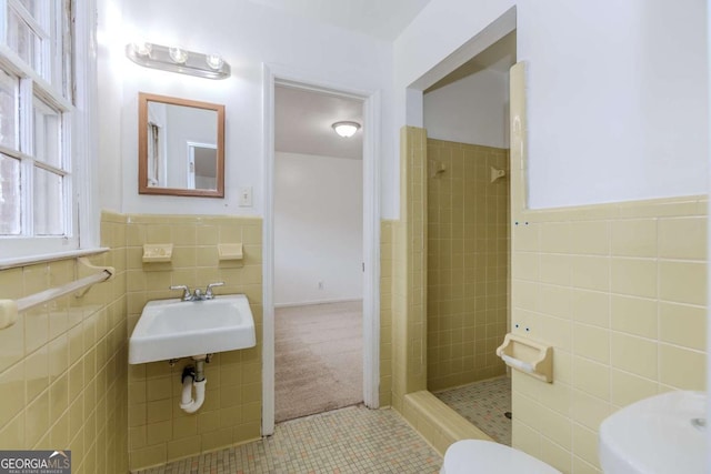 bathroom with tile walls, sink, toilet, and tiled shower