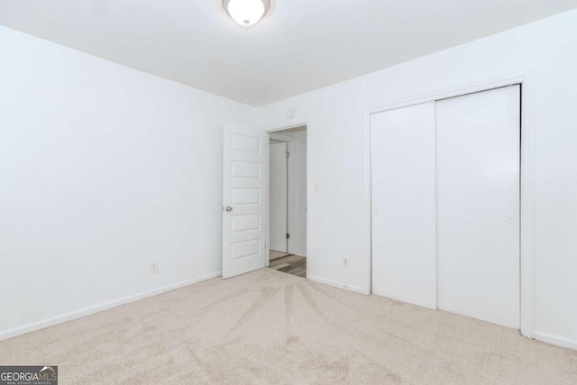 unfurnished bedroom with light colored carpet and a closet