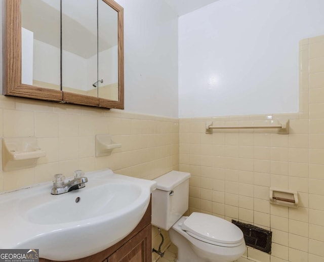 bathroom featuring vanity, tile walls, and toilet