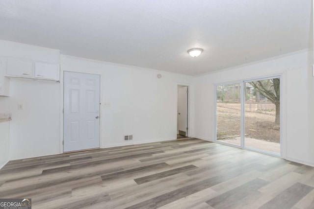 spare room featuring crown molding and light wood-type flooring