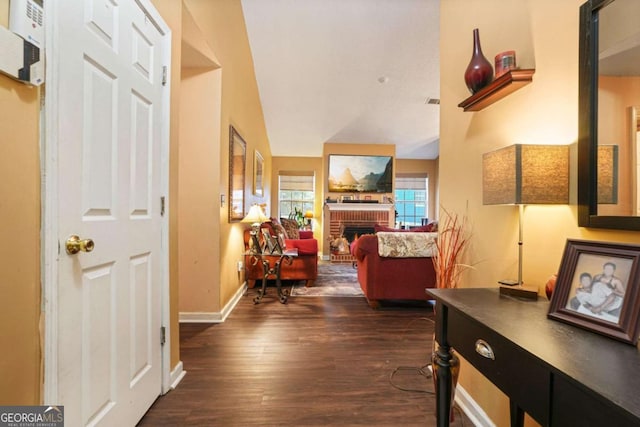 hallway with dark hardwood / wood-style floors and vaulted ceiling