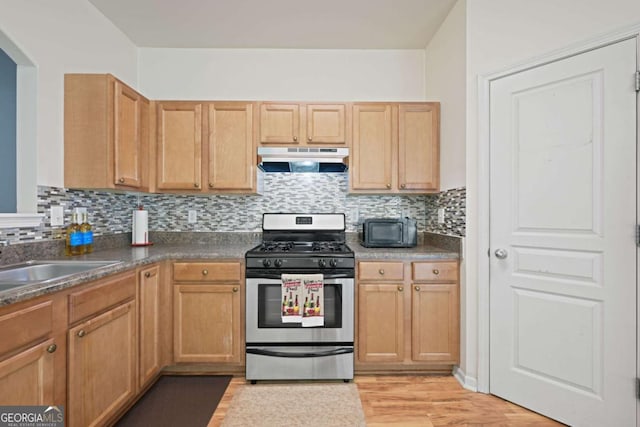 kitchen featuring light wood-type flooring, sink, stainless steel gas range, and backsplash