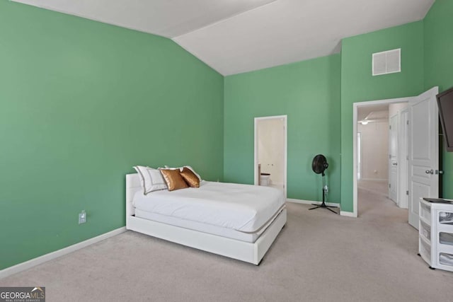 bedroom featuring lofted ceiling, light carpet, and ensuite bathroom