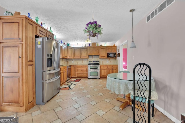 kitchen featuring stainless steel appliances, a textured ceiling, and decorative light fixtures