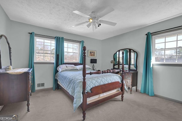 carpeted bedroom with ceiling fan and a textured ceiling