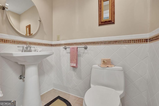 bathroom with tile walls, tile patterned floors, and toilet