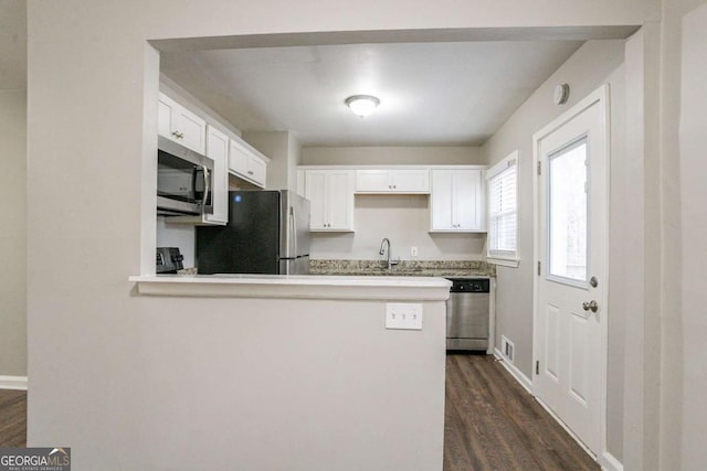 3234 Bluebird Ln, Decatur, GA 30032 - kitchen featuring white cabinetry, appliances with stainless steel finishes, dark hardwood / wood-style floors, and kitchen peninsula
