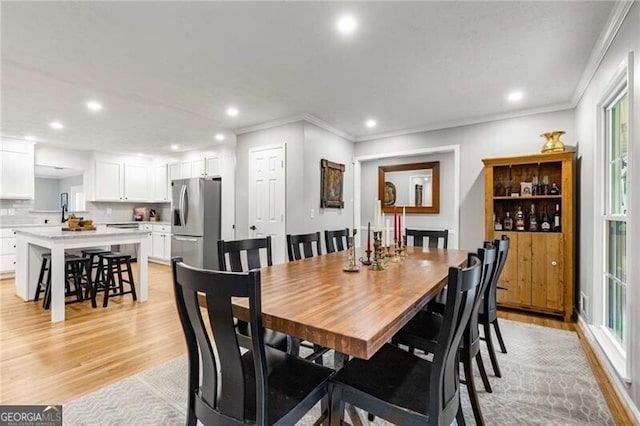 dining room with ornamental molding and light hardwood / wood-style floors