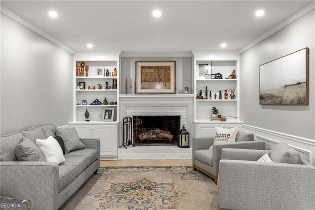 living room featuring crown molding, a brick fireplace, light hardwood / wood-style floors, and built in features