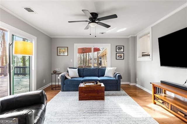 living room with ceiling fan, ornamental molding, and light hardwood / wood-style floors