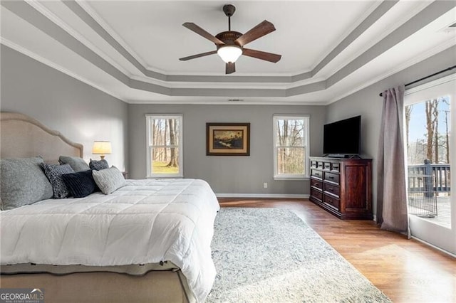 bedroom with a raised ceiling, crown molding, ceiling fan, and light hardwood / wood-style floors