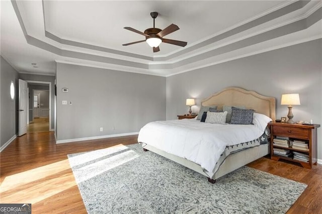 bedroom with dark wood-type flooring, ceiling fan, crown molding, and a raised ceiling