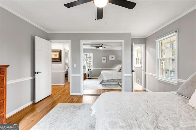 bedroom featuring ceiling fan, ornamental molding, wood-type flooring, and a closet