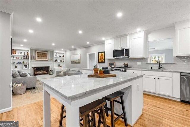 kitchen with sink, a breakfast bar area, white cabinets, and appliances with stainless steel finishes