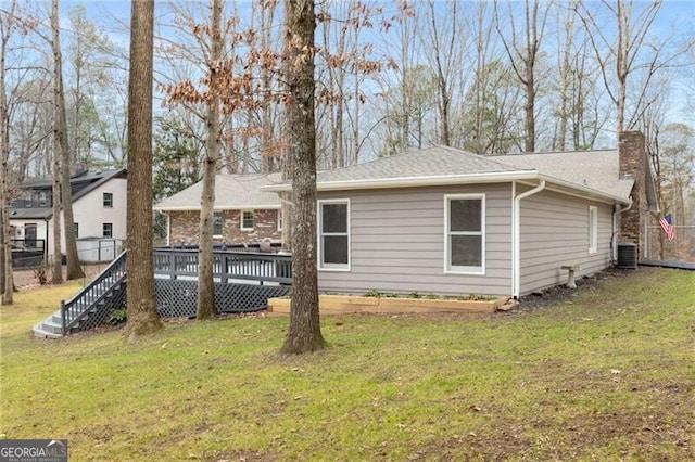 back of property with a deck, central air condition unit, and a lawn