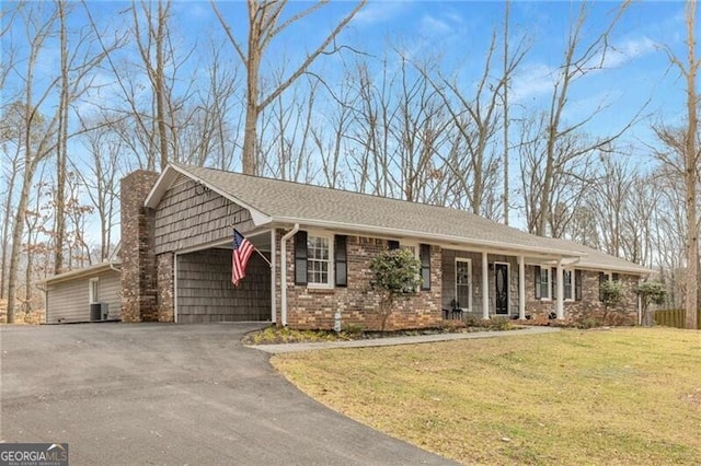 ranch-style house with a garage, covered porch, central air condition unit, and a front lawn