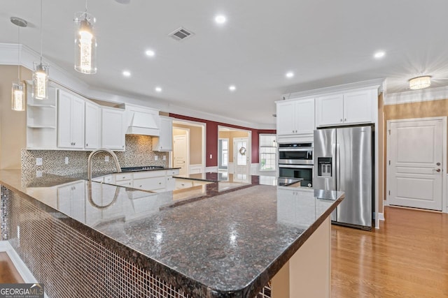 kitchen with white cabinetry, hanging light fixtures, dark stone counters, and appliances with stainless steel finishes