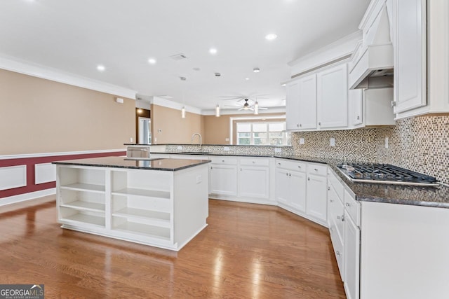 kitchen featuring premium range hood, a kitchen island, white cabinetry, stainless steel gas cooktop, and kitchen peninsula