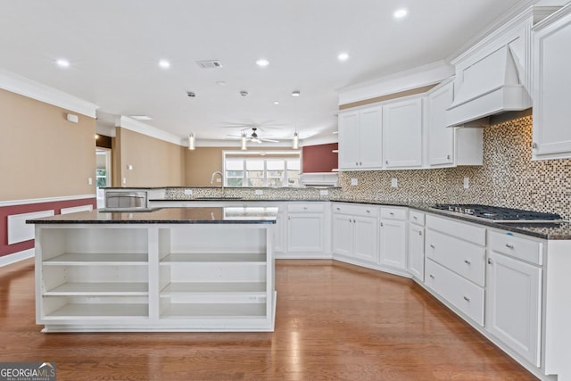 kitchen with dark stone counters, stainless steel gas cooktop, custom range hood, and white cabinets