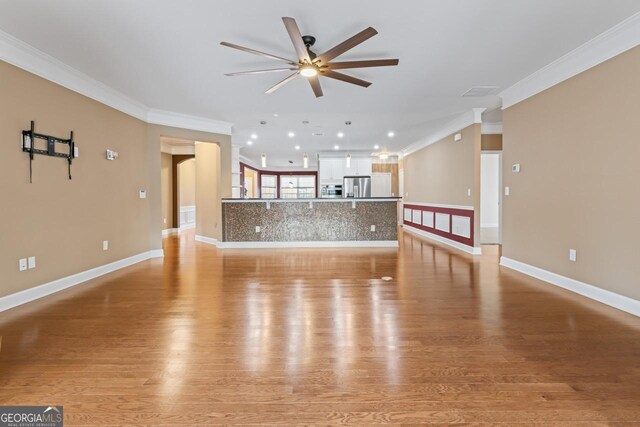 unfurnished living room with ceiling fan, ornamental molding, and light hardwood / wood-style floors