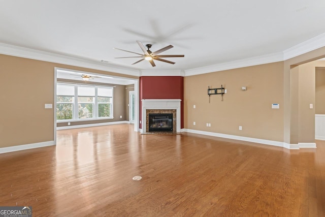 unfurnished living room with a premium fireplace, ornamental molding, light hardwood / wood-style floors, and ceiling fan