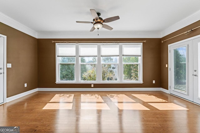 empty room featuring french doors, ornamental molding, and light wood-type flooring