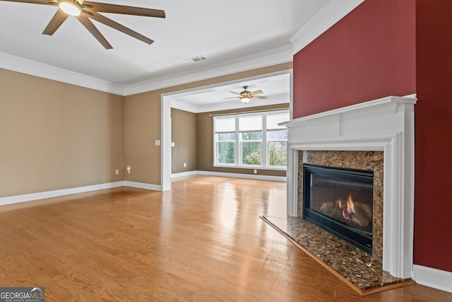 unfurnished living room with light hardwood / wood-style flooring, crown molding, a high end fireplace, and ceiling fan