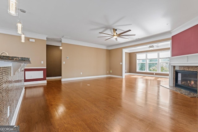 unfurnished living room featuring a premium fireplace, wood-type flooring, and crown molding