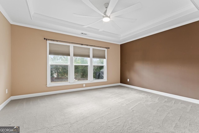 carpeted spare room with a raised ceiling, ornamental molding, and ceiling fan