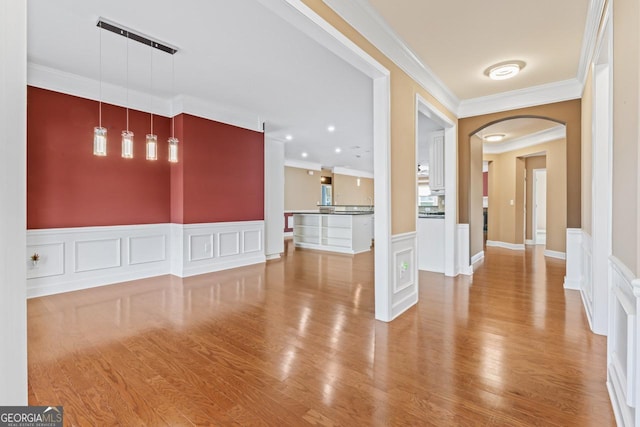 unfurnished living room with ornamental molding and light hardwood / wood-style floors