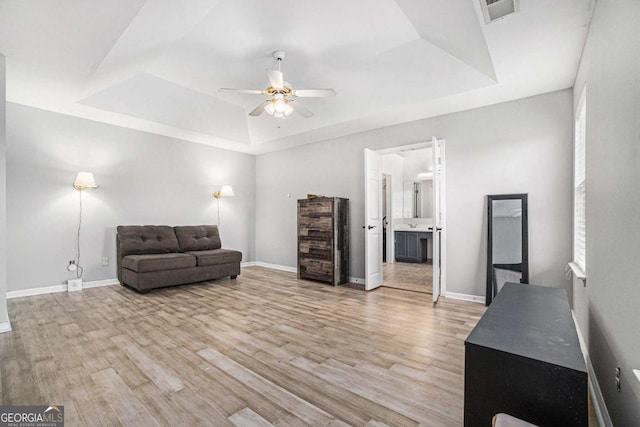 living room featuring a tray ceiling, light hardwood / wood-style flooring, and ceiling fan