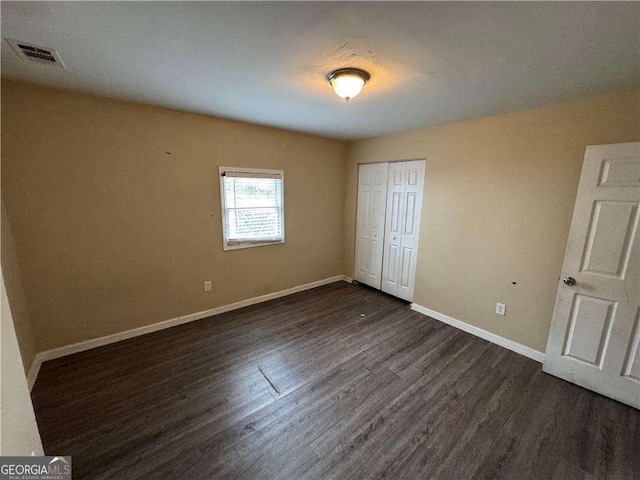 unfurnished bedroom featuring dark wood-type flooring and a closet