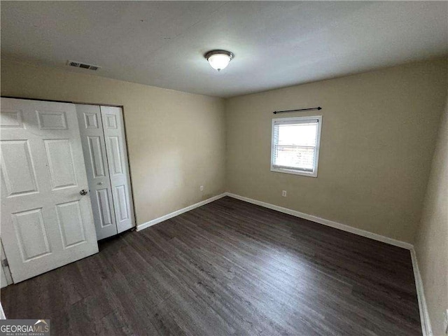 unfurnished bedroom with dark hardwood / wood-style flooring and a closet