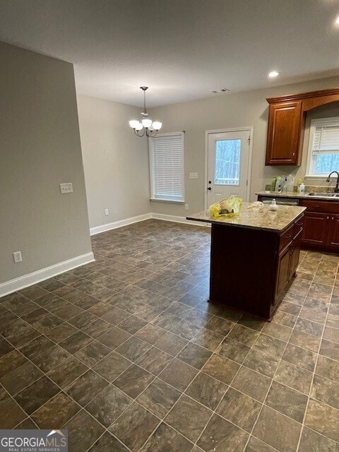 kitchen featuring sink, light stone counters, a chandelier, a kitchen island, and pendant lighting