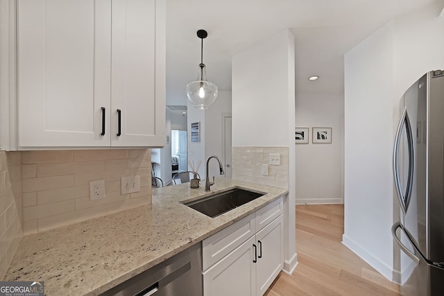 kitchen featuring appliances with stainless steel finishes, light stone countertops, sink, and white cabinets