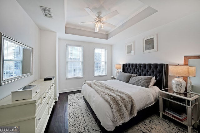 bedroom with a raised ceiling, ornamental molding, dark hardwood / wood-style floors, and ceiling fan