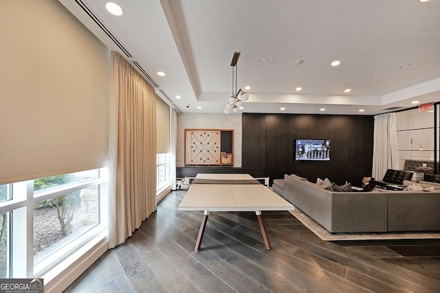 living room with a tray ceiling, wood-type flooring, and wooden walls