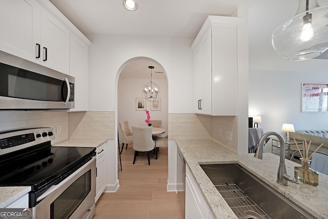 kitchen featuring sink, white cabinetry, hanging light fixtures, stainless steel appliances, and light stone counters