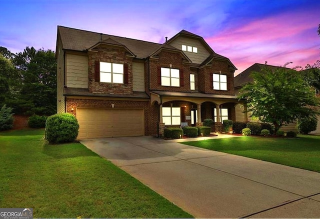 view of front of home with a garage, brick siding, driveway, and a front yard