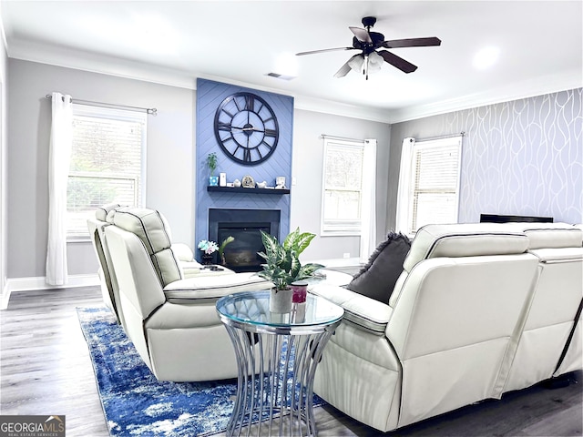 living room featuring crown molding, plenty of natural light, a fireplace, and hardwood / wood-style flooring