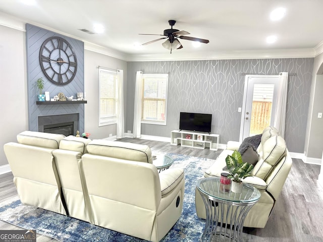 living room with crown molding, hardwood / wood-style floors, ceiling fan, and a fireplace