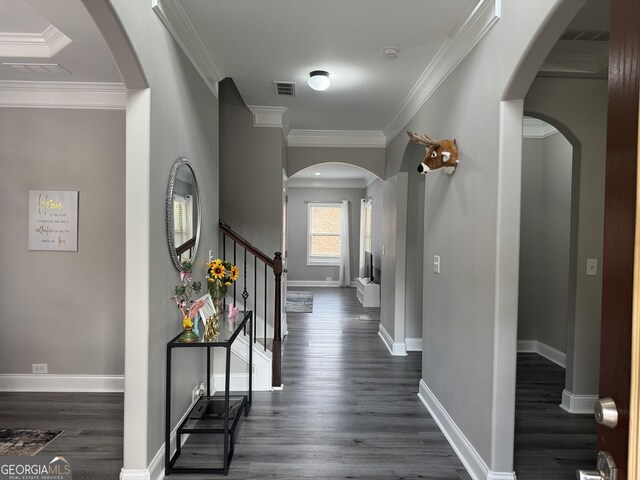 corridor with dark wood-style floors, baseboards, arched walkways, and crown molding