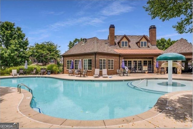 pool with french doors and a patio area